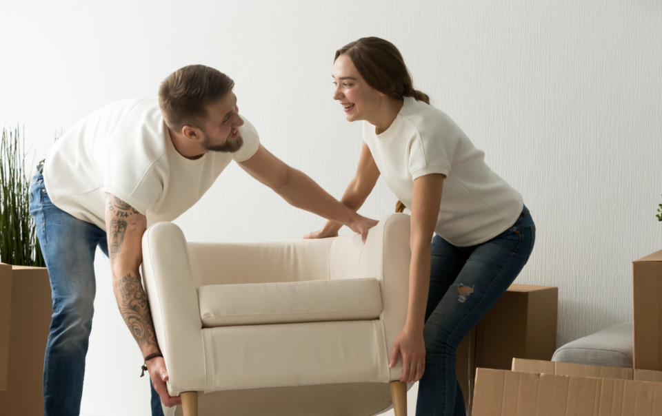 Two people moving a white couch